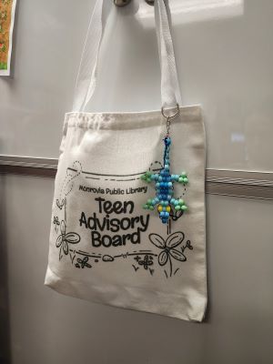 a tote bag with a beaded lizard hanging off the strap