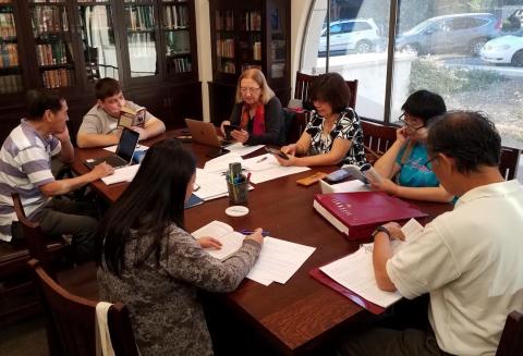 Various people with laptops and papers discussing during literacy book writing club